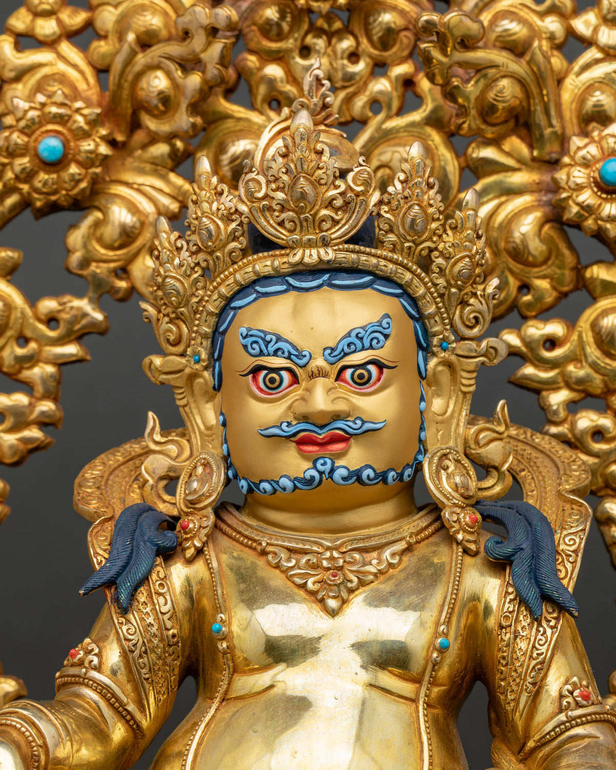 Close-up of enthroned Yellow Dzambhala statue with foliage aureole, hand-carved gilded copper from Nepal