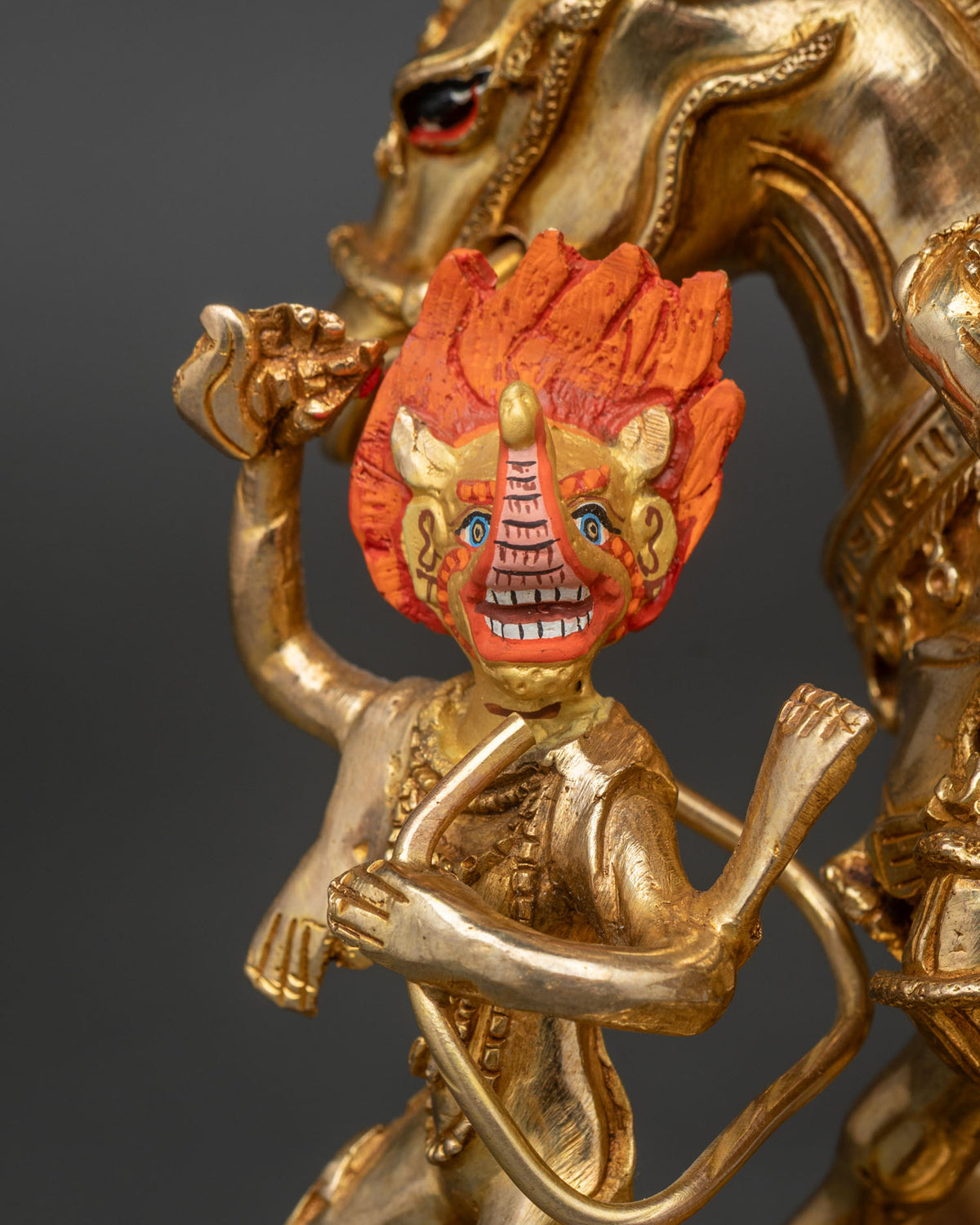 Close-up of fire-gilded attendant with fierce orange-red face beside Palden Lhamo statue