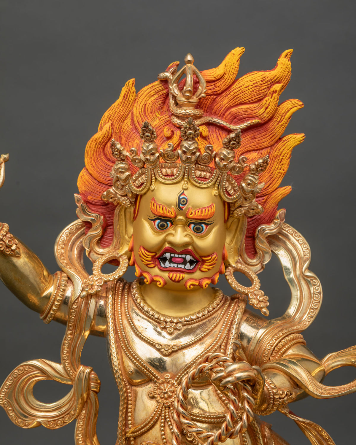 Close up of fire-gilded Vajrapani statue showing vajra, lasso and flowing garments