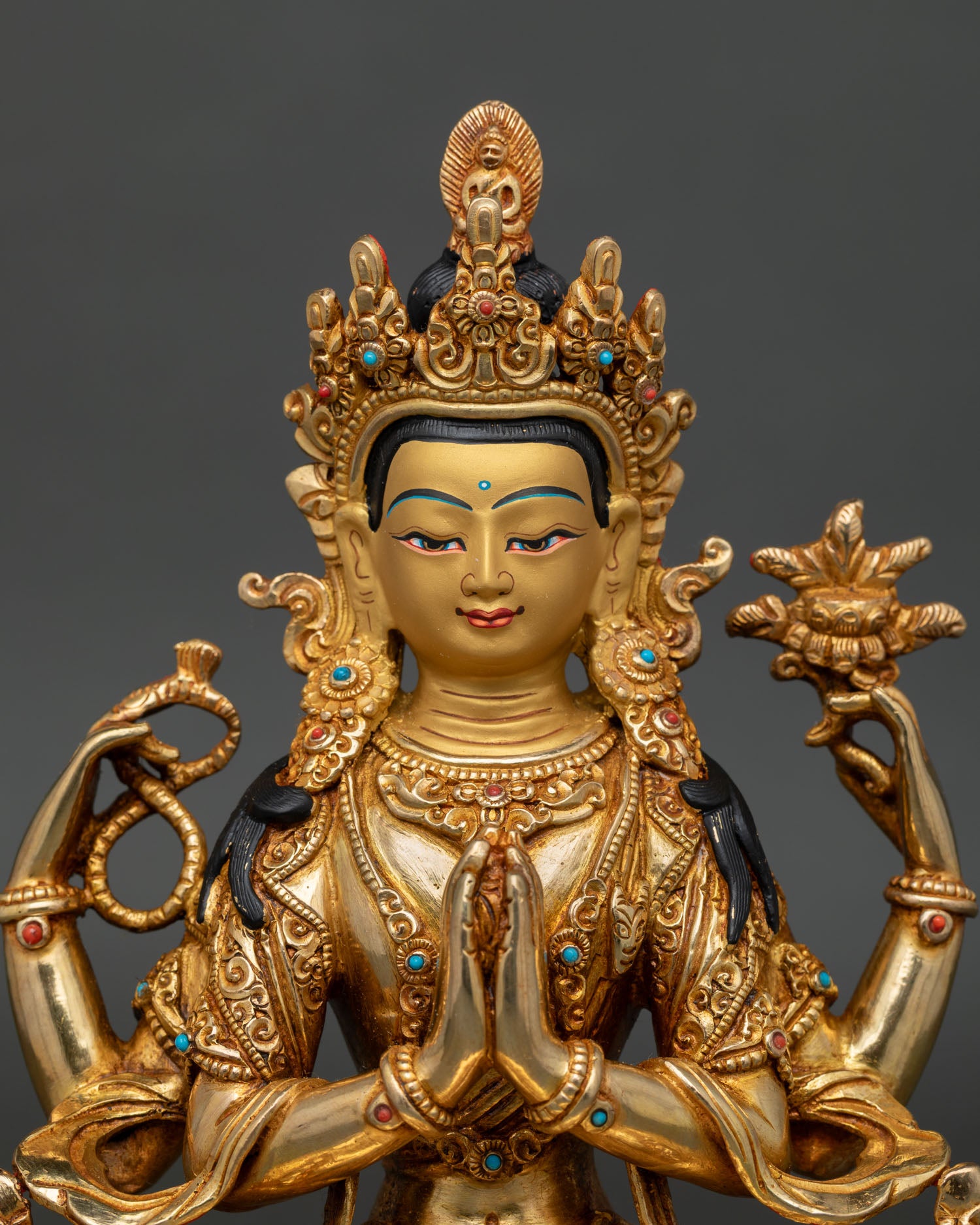 Close-up of four armed Chenrezig statue with gold painted face and crystal rosary