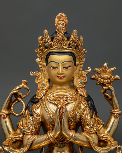 Close-up of four armed Chenrezig statue with gold painted face and crystal rosary