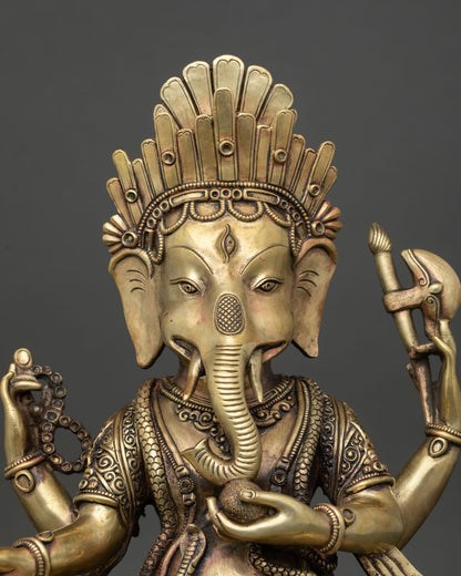 Close up of four-armed copper Ganesh idol holding traditional attributes on lotus throne.