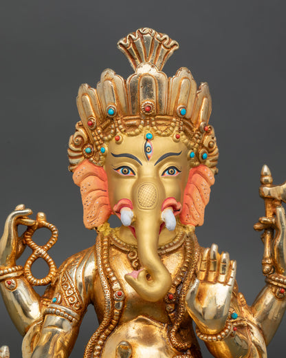 close up of four armed ganesha statue with gold gilding and sacred jewelry