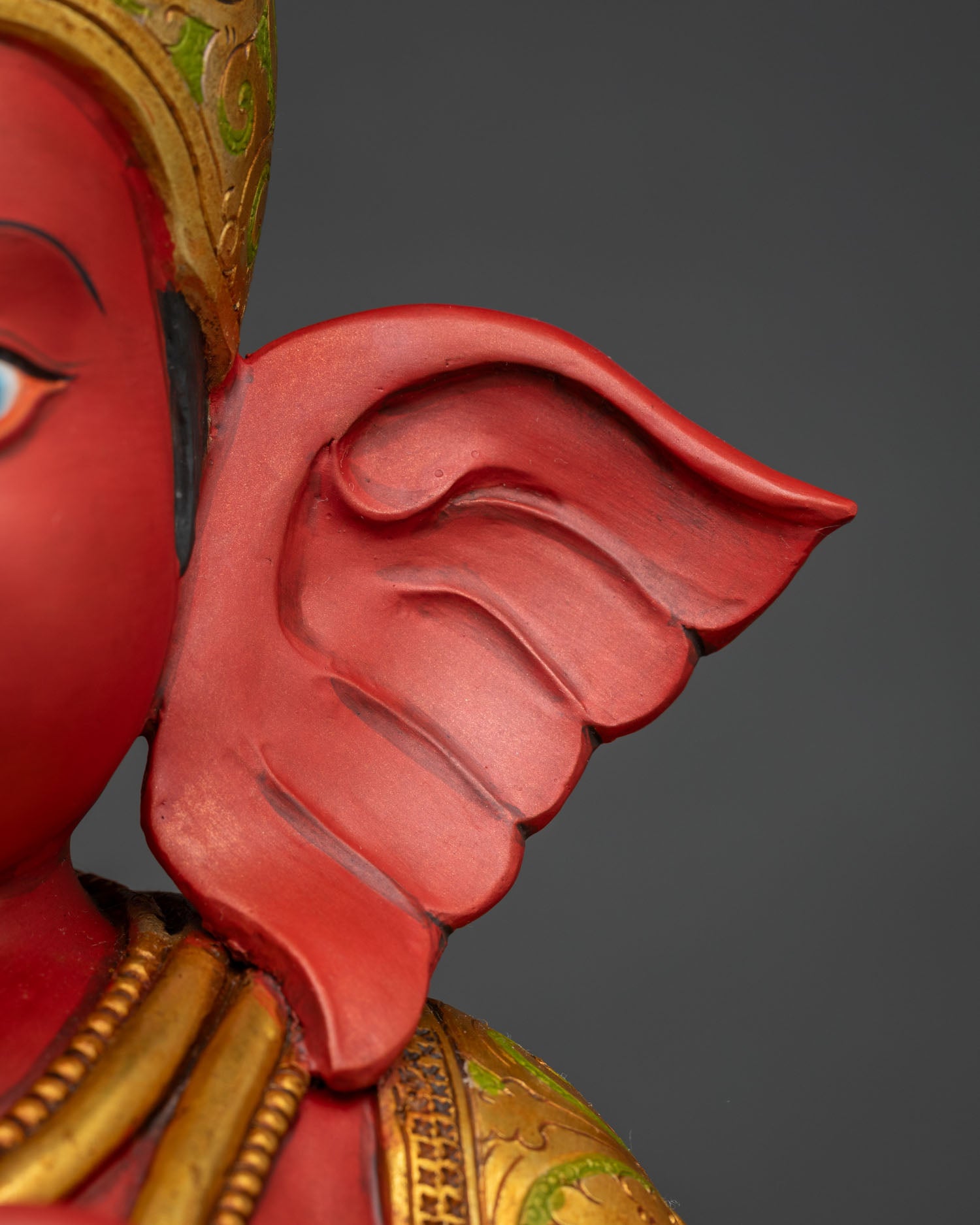 Close-up of Ganesha statue elephant ear showing hand-painted red finish