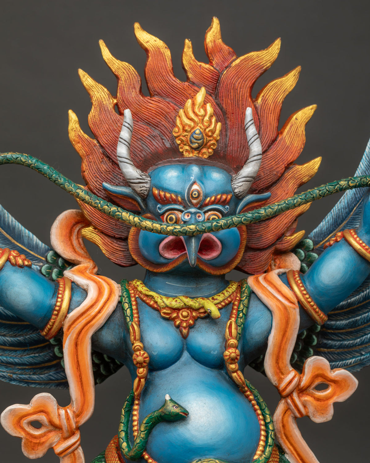 Close up of Garuda statue showing carved wings and serpent details