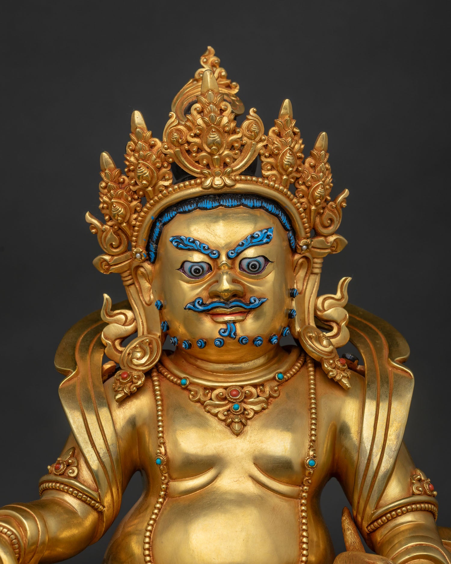 Close-up of gold fire gilded copper Dzambhala statue showing crown and ornaments