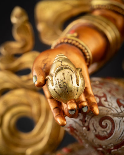 Close-up of gold-gilded citron fruit held by Yellow Dzambhala statue