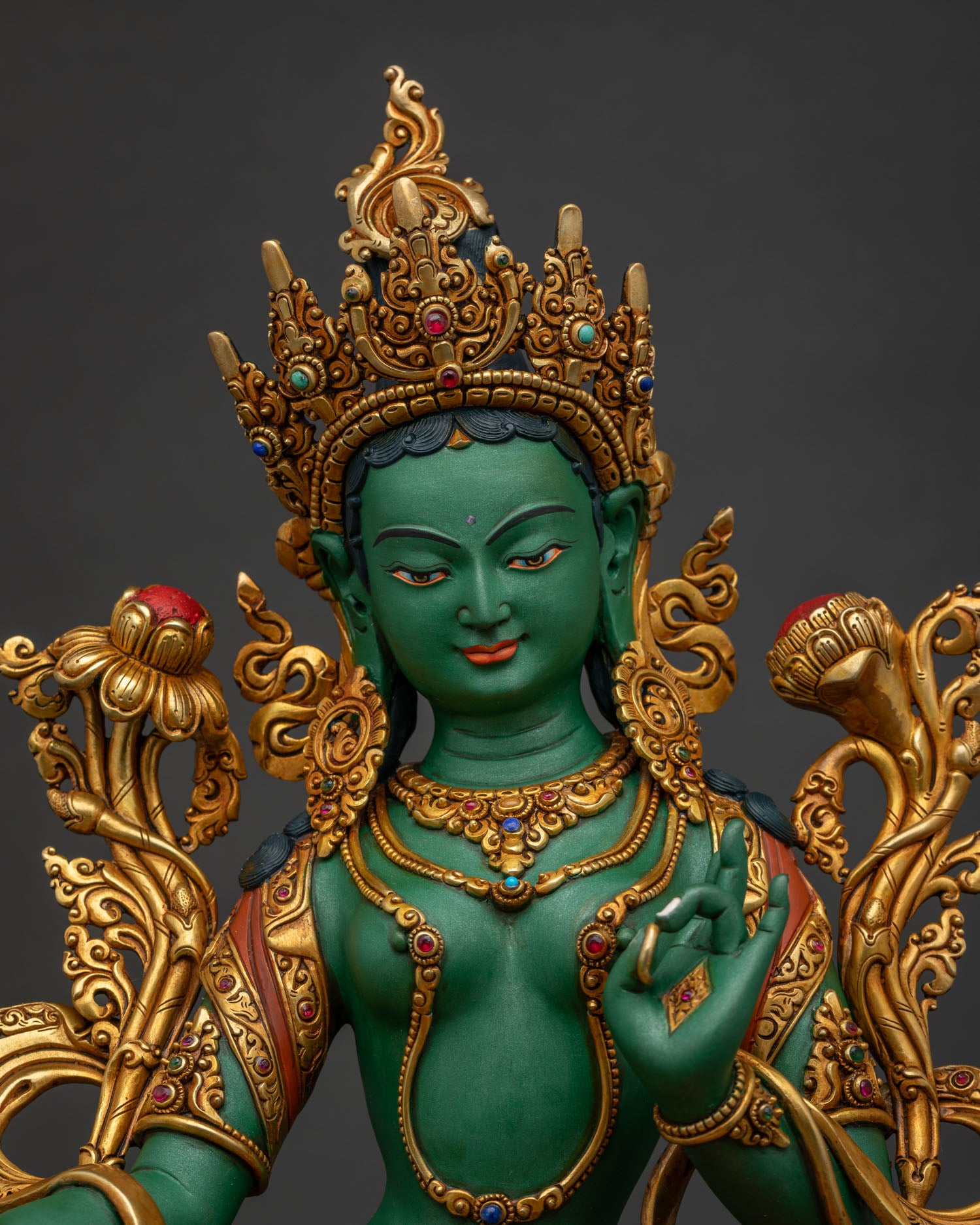 Close-up of gold-gilded Green Tara idol adorned with semi-precious stones