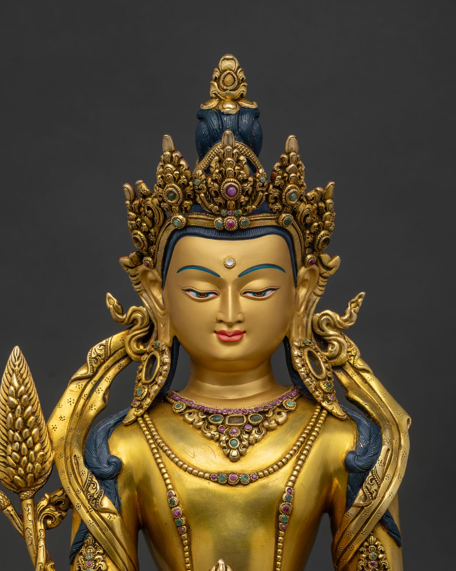 Close-up of gold gilded Ksitigarbha statue with semi-precious gemstones and copper details