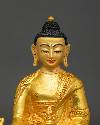 close up of gold gilded medicine buddha face with serene expression and robes