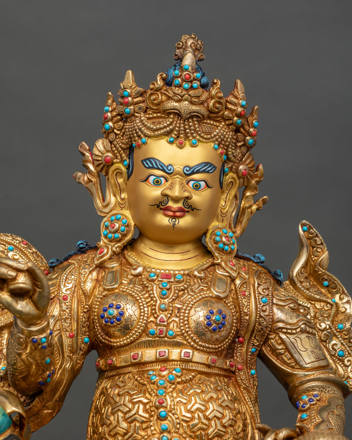 Close-up of gold-gilded Namtoshe statue seated on a snow lion with gemstone-inlaid armor