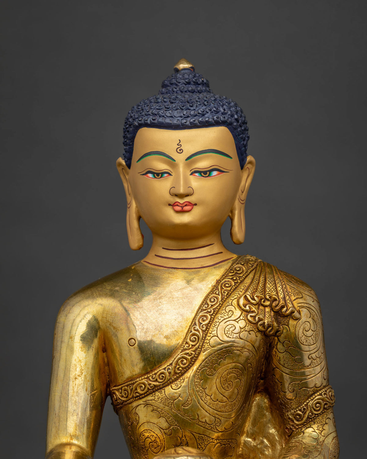 Close-up of gold-gilded Shakyamuni Buddha statue showing lotus seat and monastic robe detail