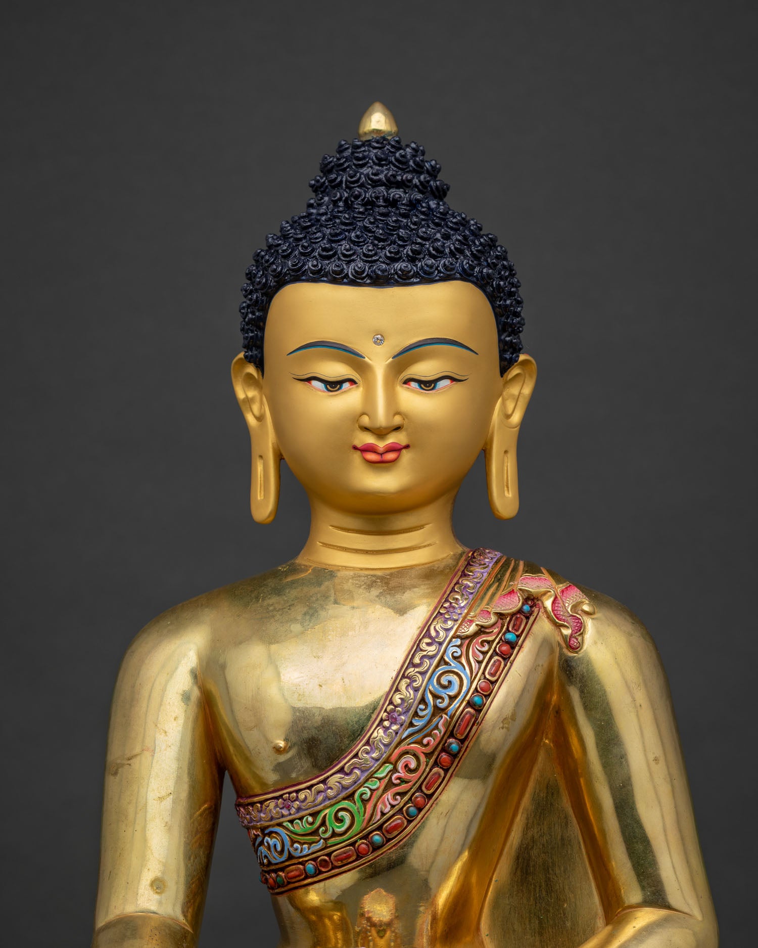 Close up of gold-gilded Shakyamuni Buddha statue with hand-painted monastic robe