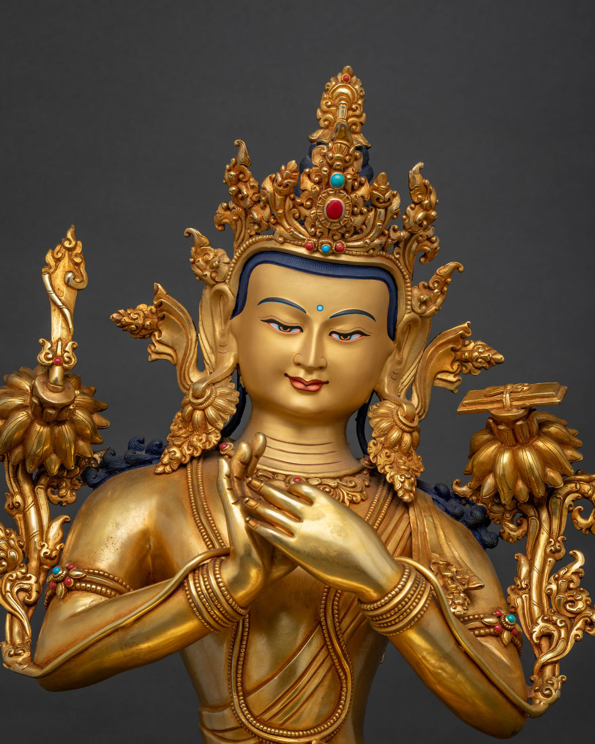Close-up of gold Manjushri statue's jeweled crown and hands in Dharmachakra mudra