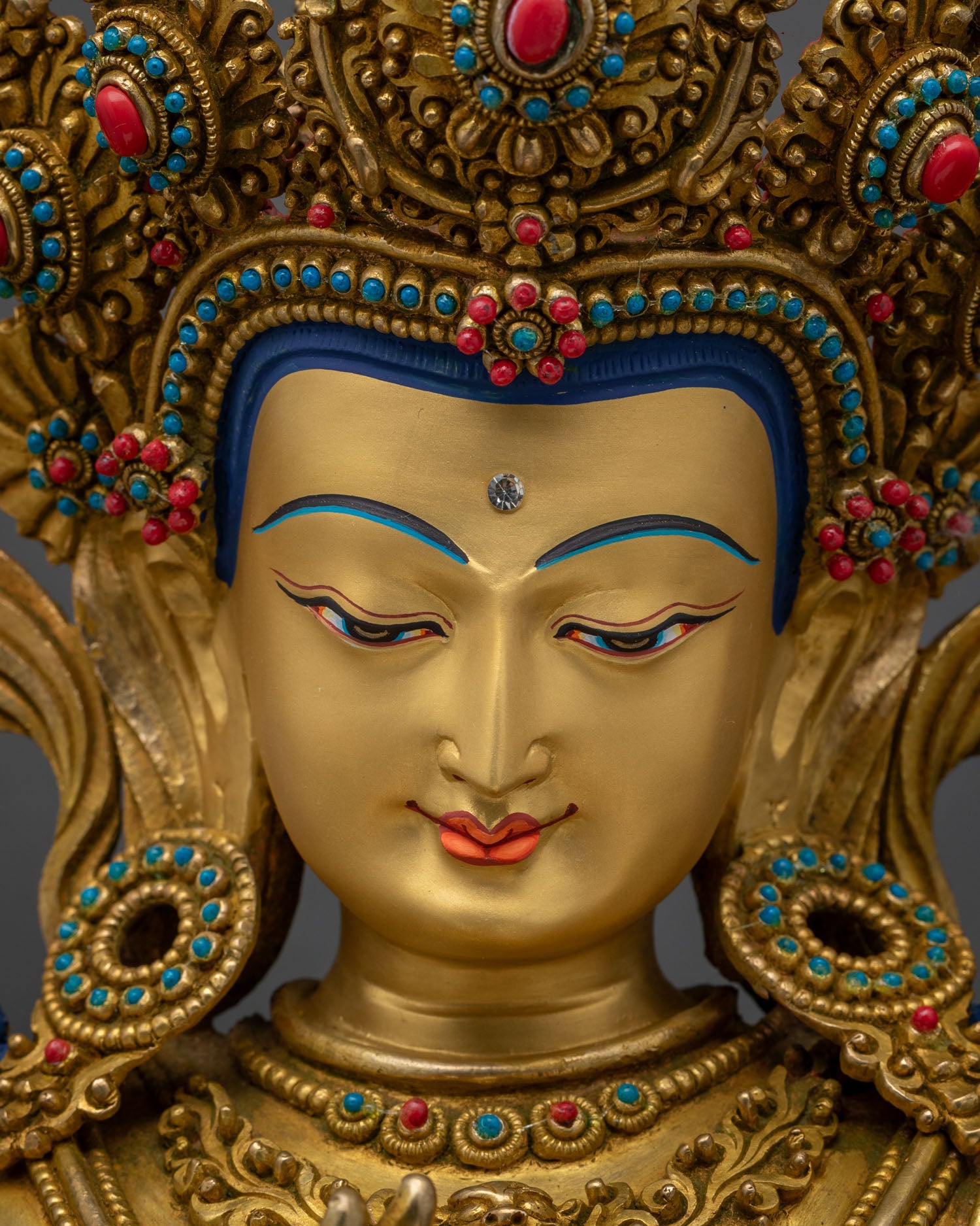 Close-up of gold-painted face and gemstone crown on Tikshna Manjushri statue