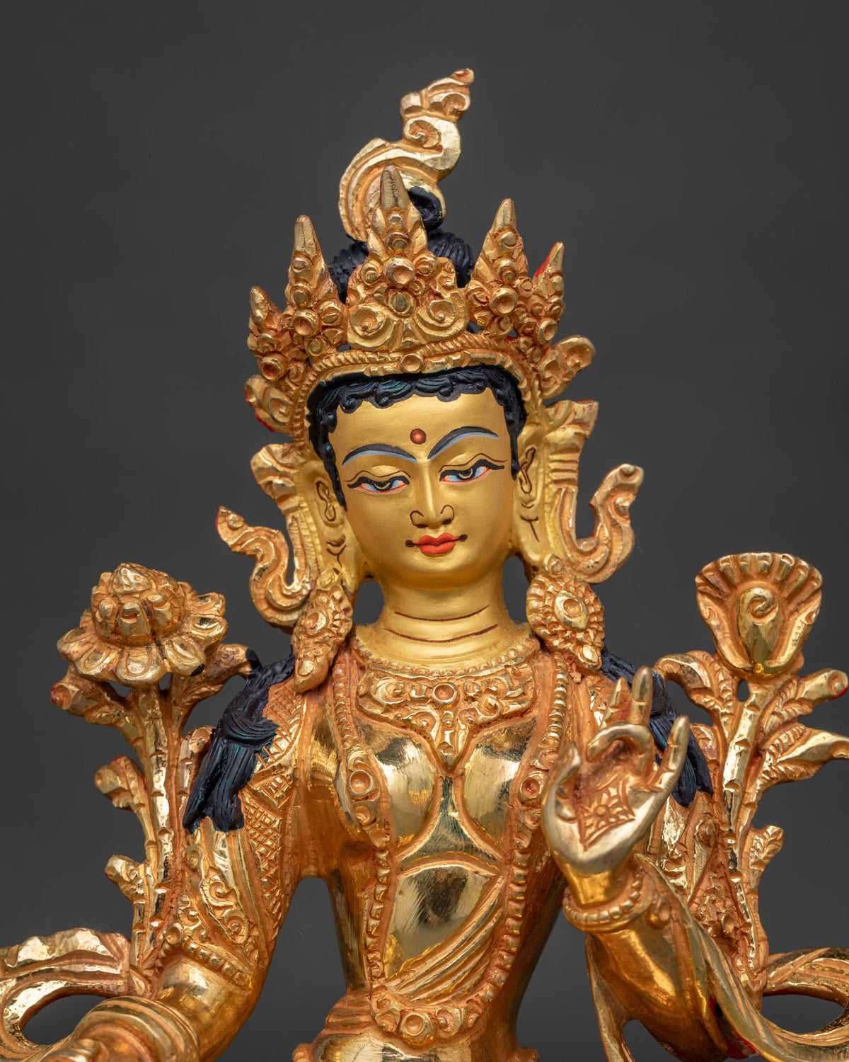Close up of Green Tara 24k gold painted face with serene expression and ornate jewelry.