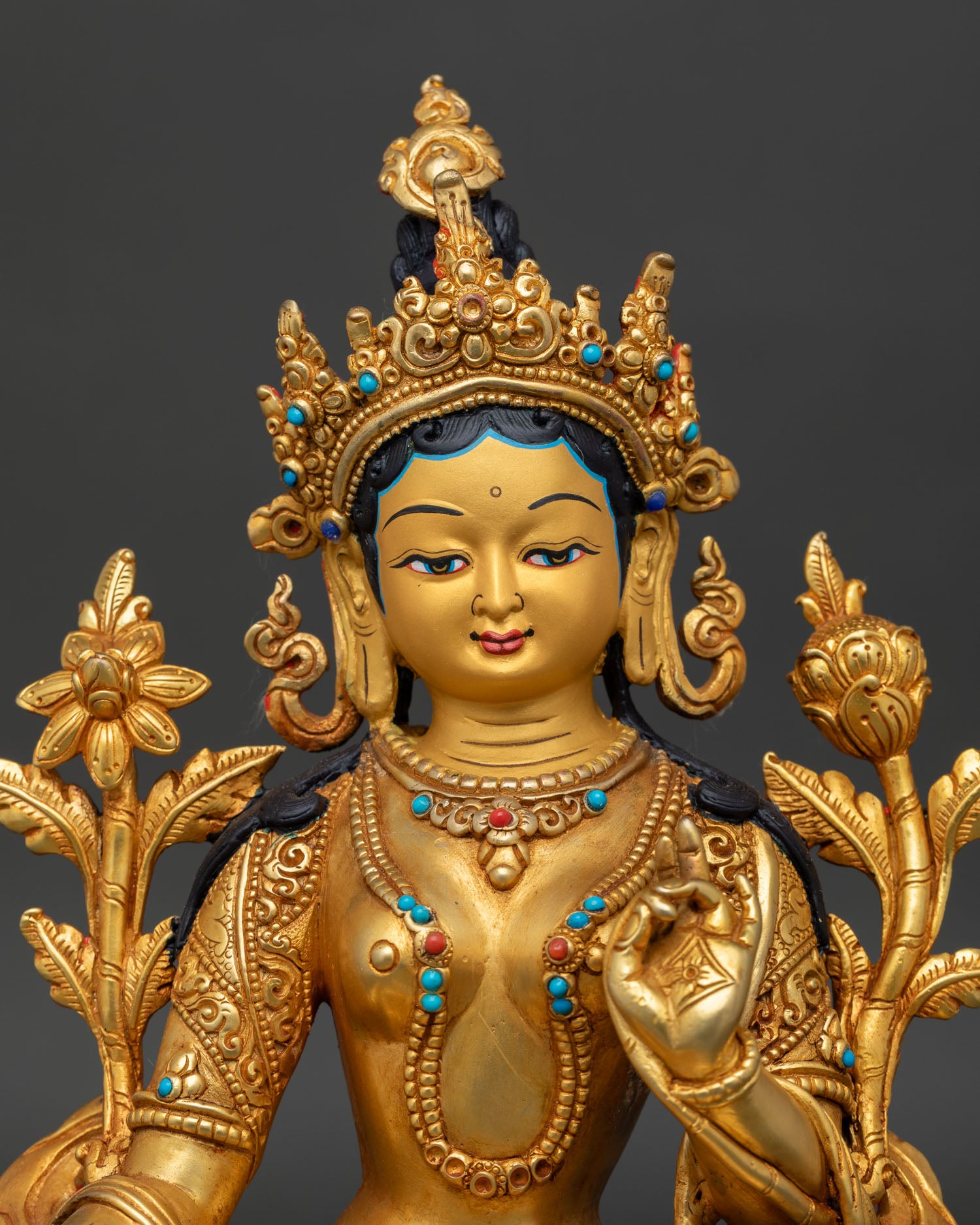 Close-up of Green Tara Buddhist statue with gold gilded details and sacred ornaments