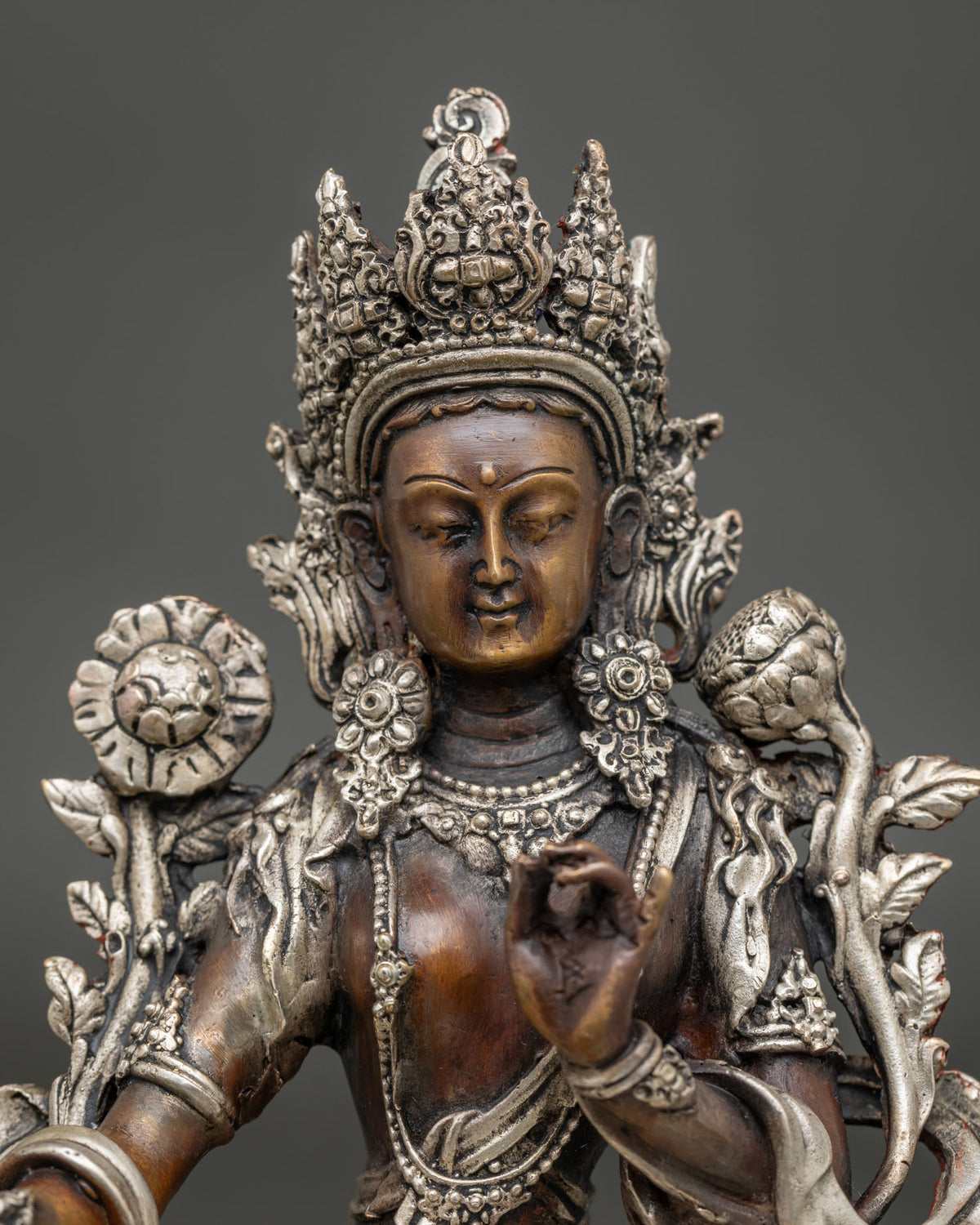 Close-up of Green Tara copper statue with silver-plated crown, floral earrings and necklace