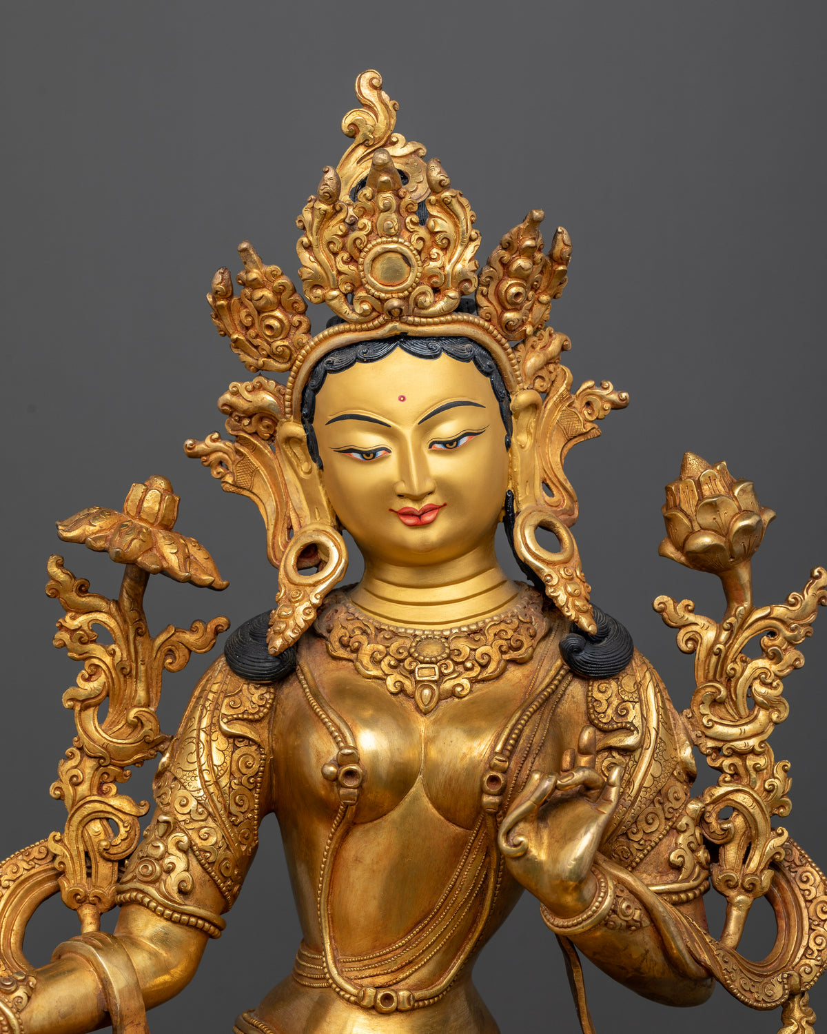 Close up of Green Tara face with 24K gold painting and detailed traditional jewelry.