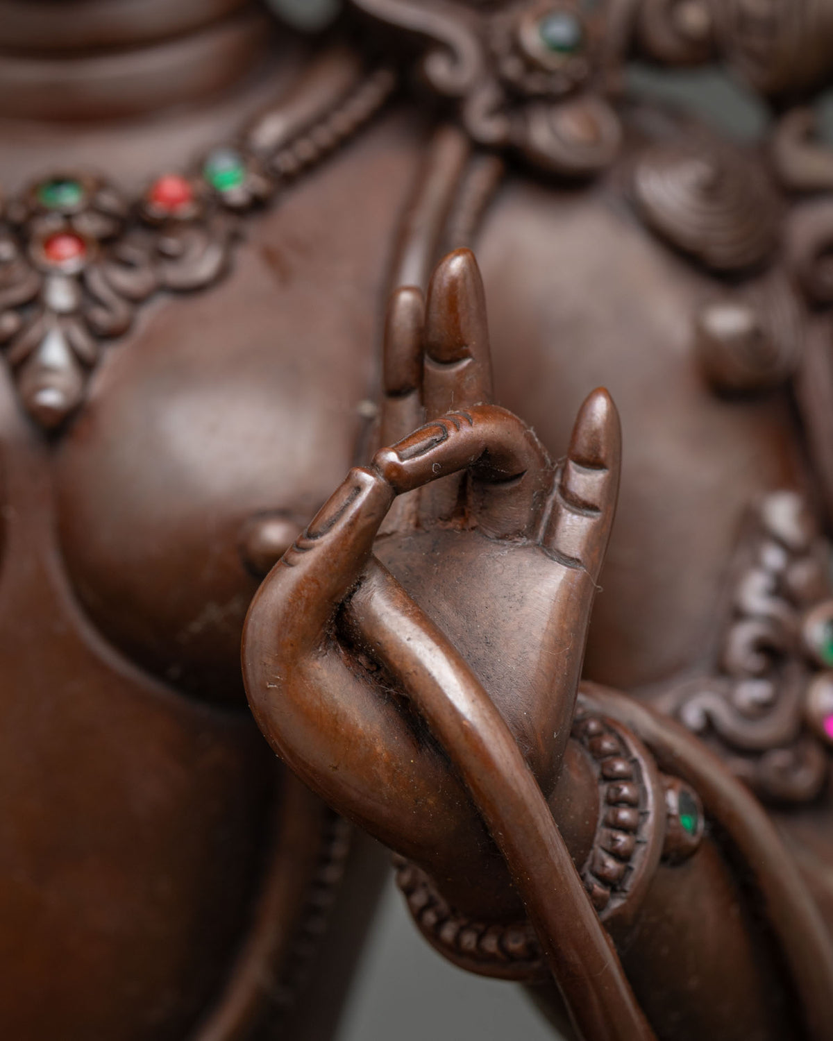 Close up of Green Tara hand mudra and traditional copper jewelry