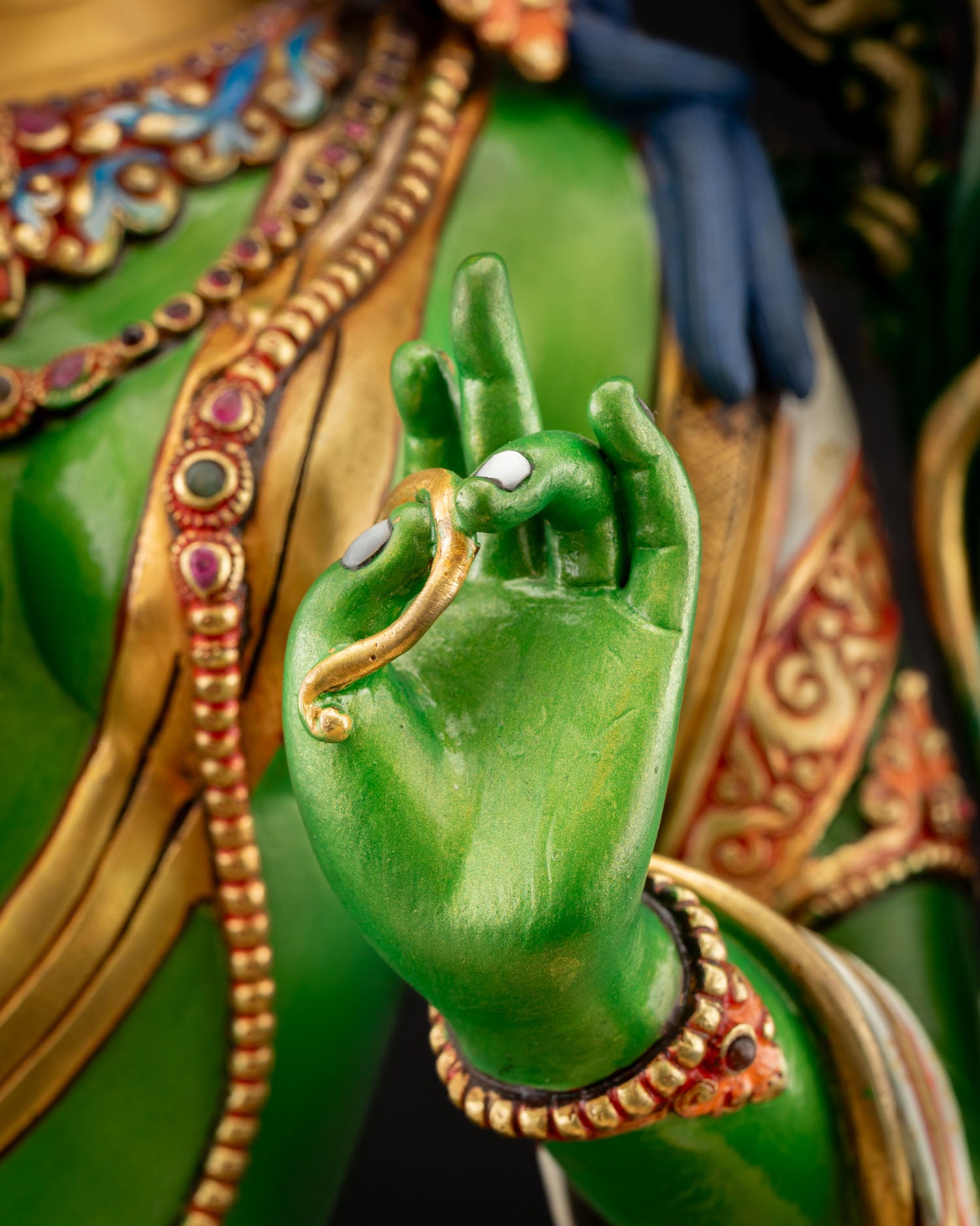 Close‑up of Green Tara left hand in Abhaya Mudra, palm raised signifying protection and liberation