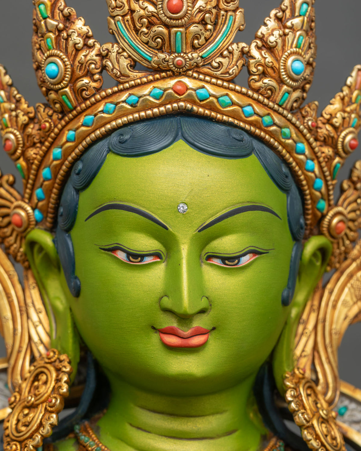 Close-up of Green Tara statue’s extended foot resting on turquoise-inlaid gilded lotus, copper sculpture