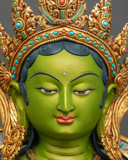 Close-up of Green Tara statue’s extended foot resting on turquoise-inlaid gilded lotus, copper sculpture