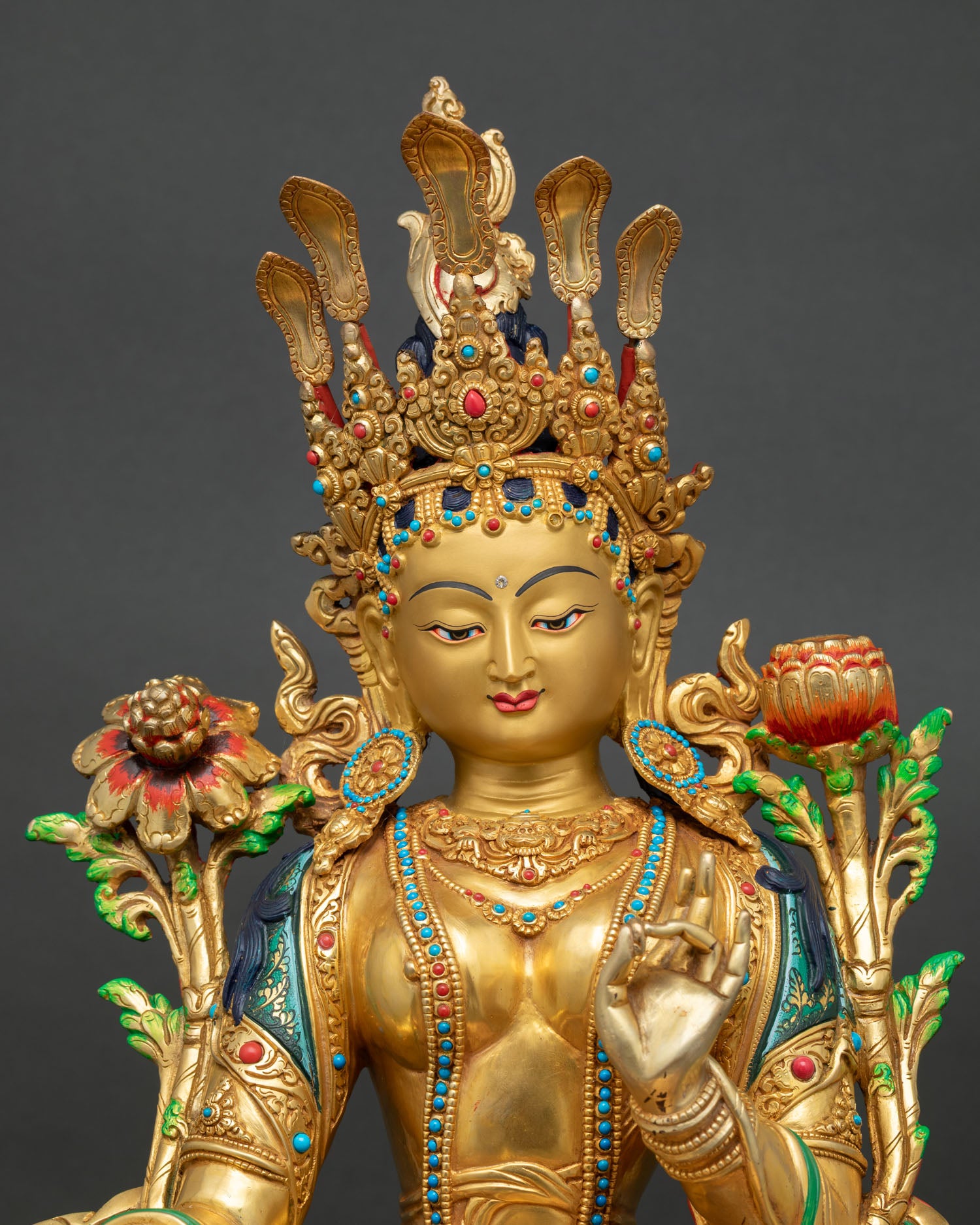 Close-up of Green Tara statue face with jeweled crown, vitarka mudra, turquoise coral inlays
