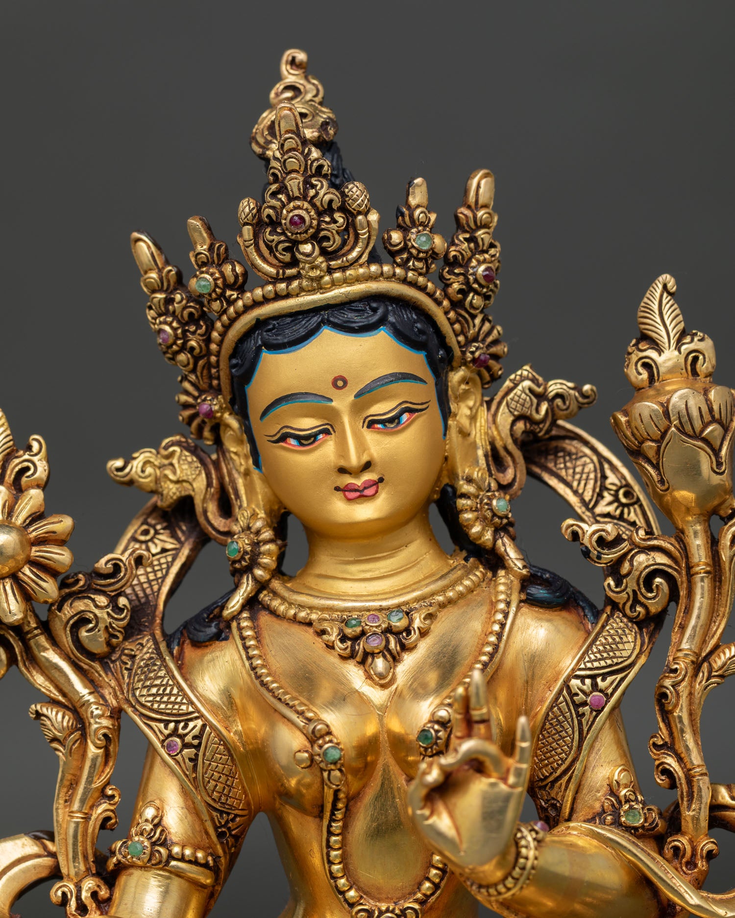 close up of green tara statue highlighting intricate copper craftsmanship and radiant gold gilded finish