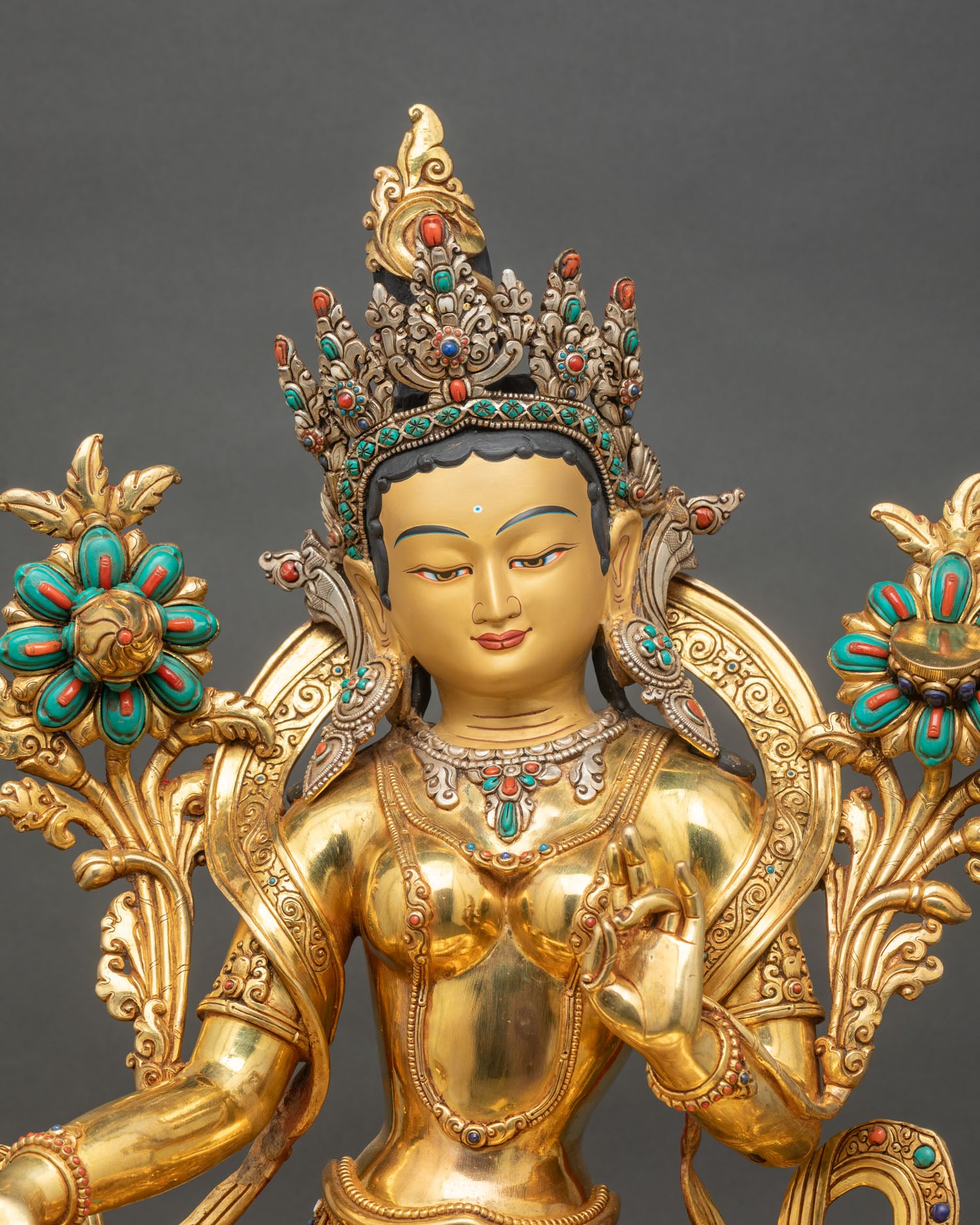 Close up of Green Tara statue showing gold gilding, crown and jewelry details