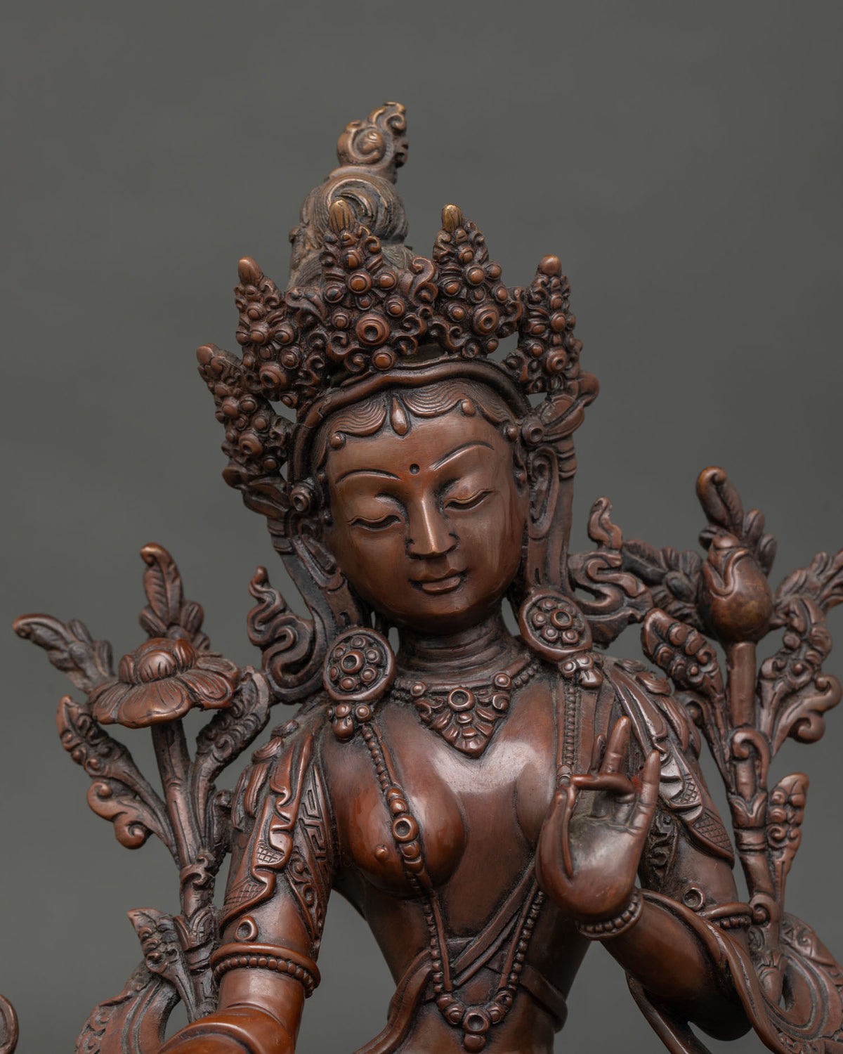 Close up of Green tara statue showing varada mudra and utpala lotus.
