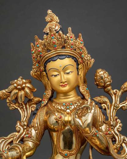 Close up of Green Tara statue with crown and utpala flower, gold gilded copper from Nepal