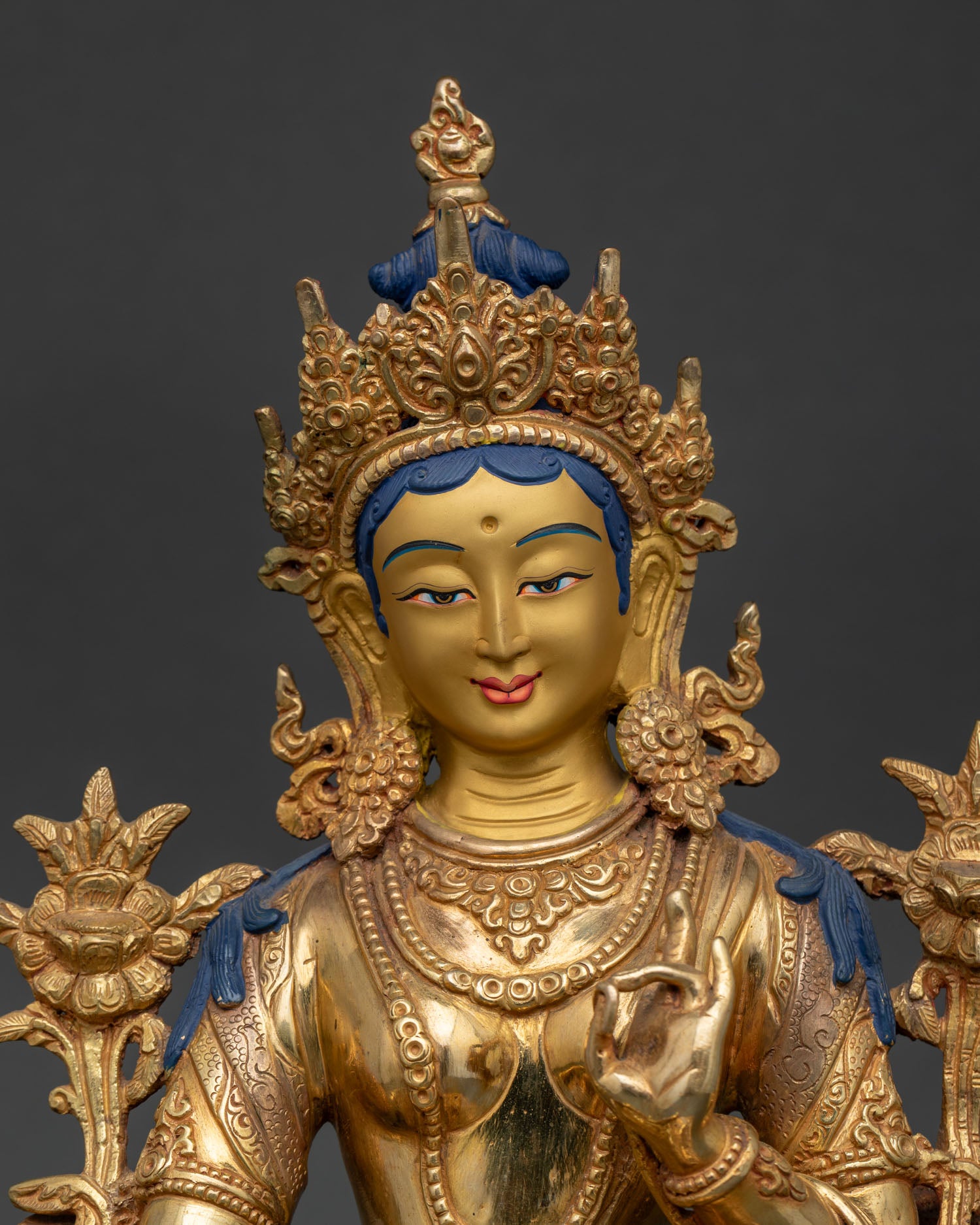 Close Up of Green Tara Statue with Gold Painted Face and Peaceful Expression