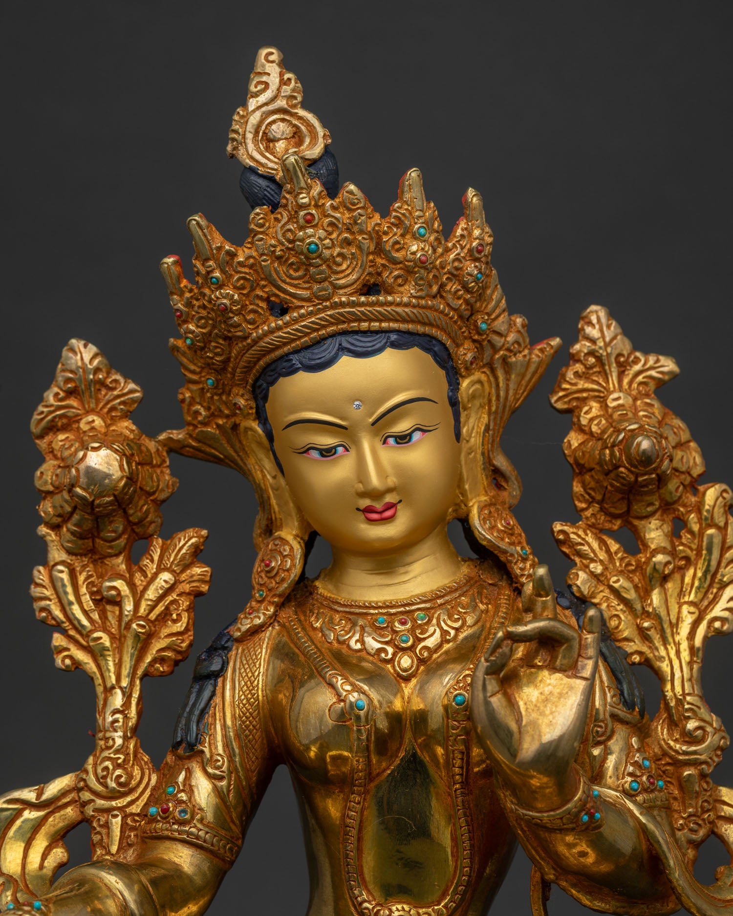 Close up of Green Tara Statue with gold painted face and semi precious stones