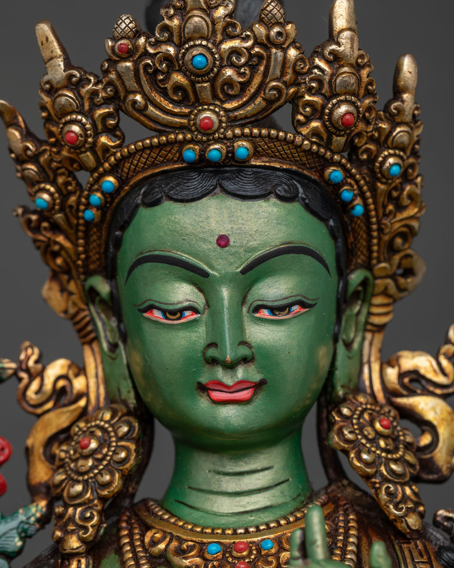 Close-up of Green Tara statue's serene face and five-jeweled crown