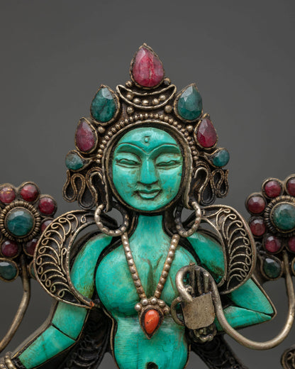 Close up of Green Tara turquoise face and jeweled crown on handcarved Buddhist figurine