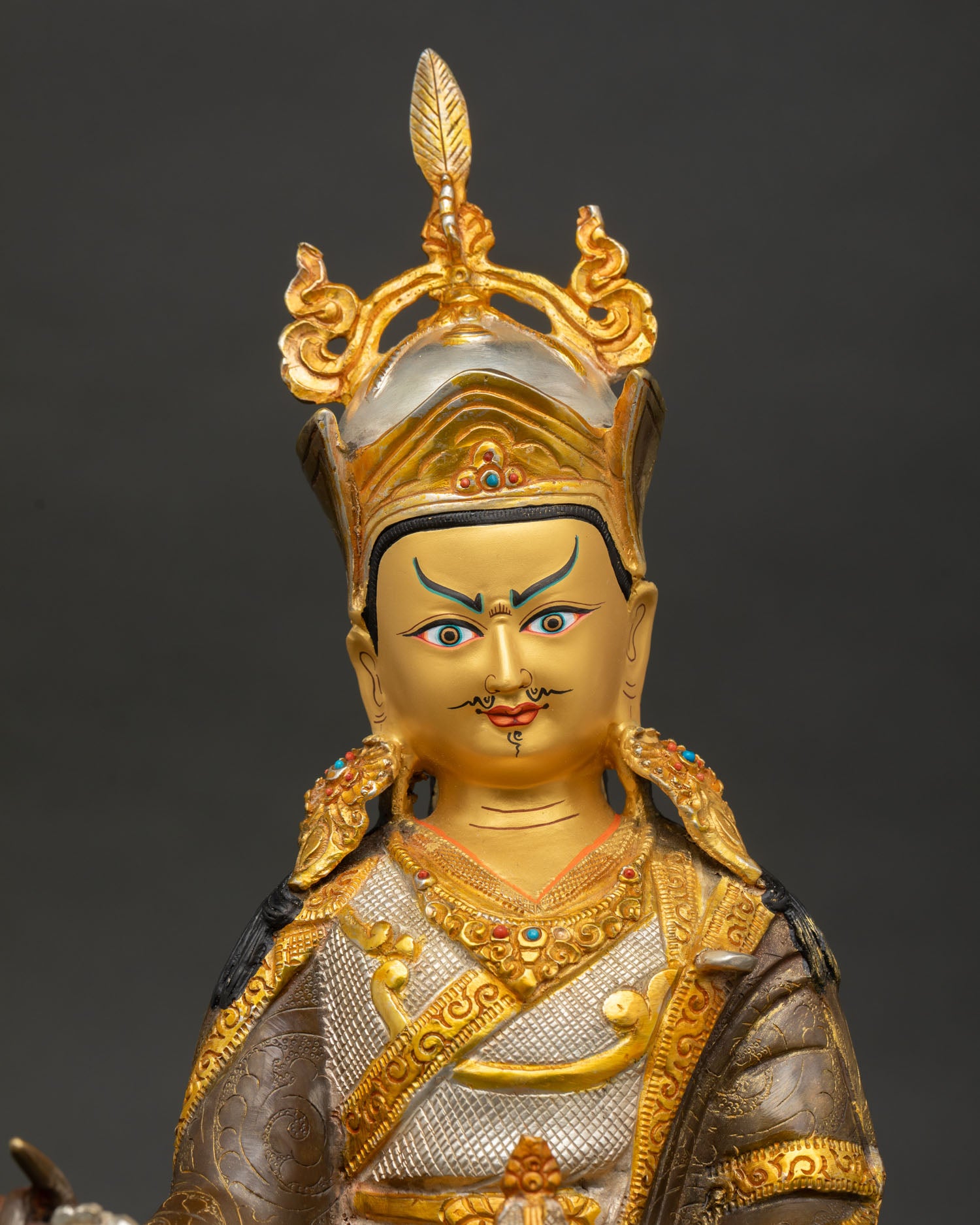 Close-up of Guru Padmasambhava Statue showing semi-wrathful expression and sacred ornaments.