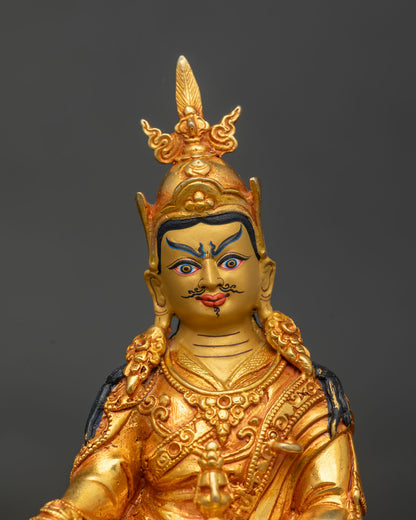 Close-up of Guru Rinpoche face with gold paint, black mustache and ornate feathered crown