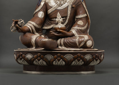 Close-up of Guru Rinpoche hand holding a silver-plated vajra with hand-chased carving.