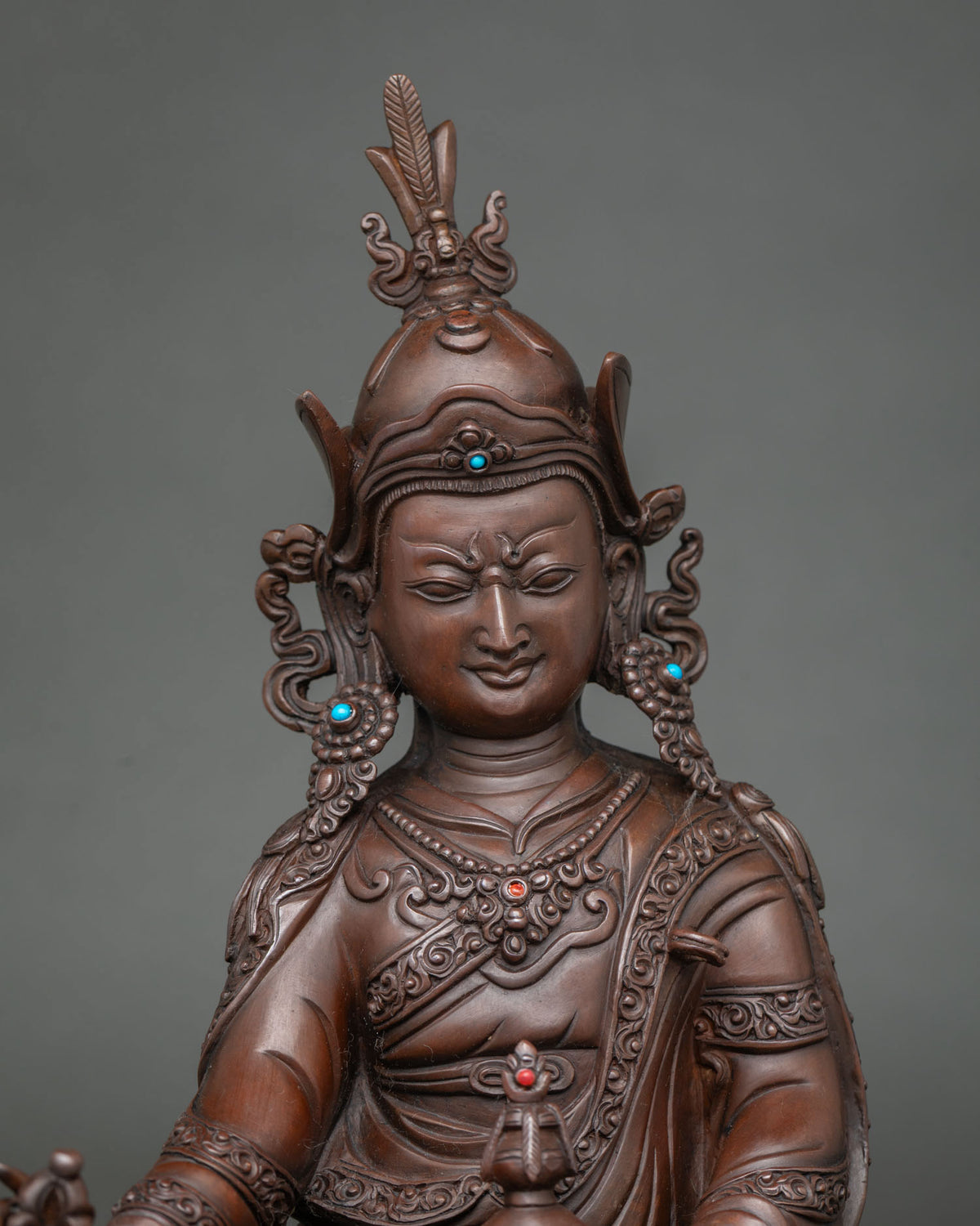 Close-up of Guru Rinpoche statue’s face and lotus hat with inlaid stones