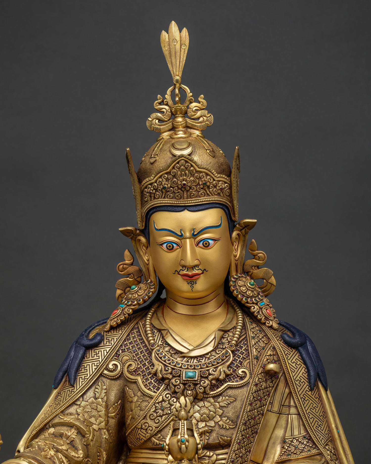 Close-up of Guru Rinpoche statue holding vajra and kapala skull cup