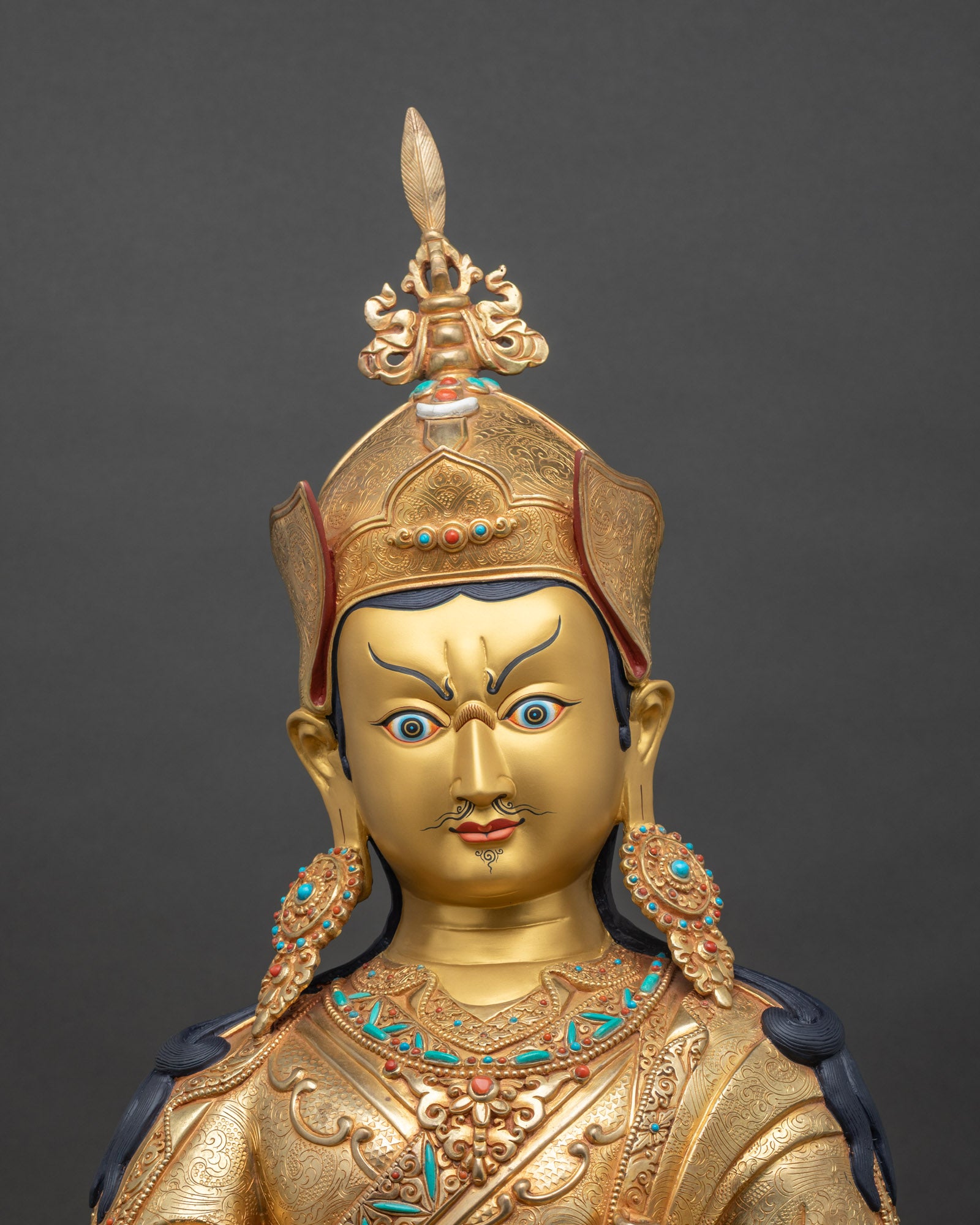 Close up of Guru Rinpoche statue showing gold gilding copper details and turquoise coral stones