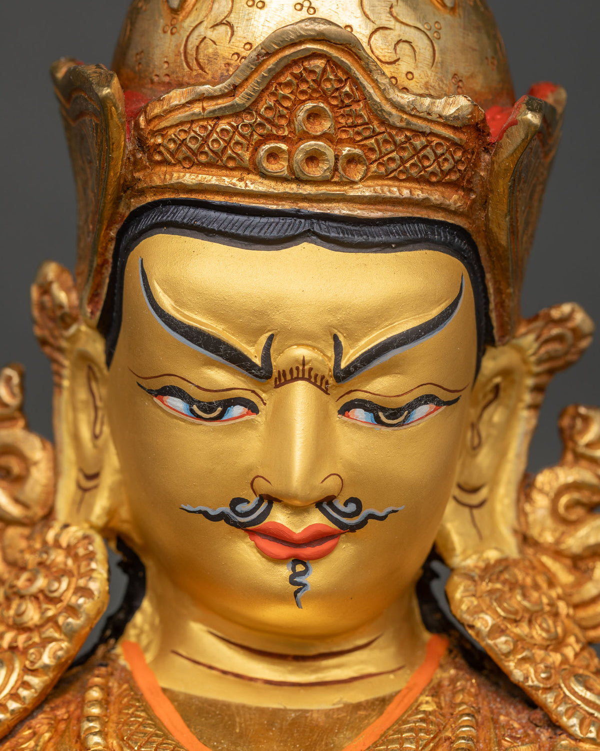 Close-up of Guru Rinpoche Tsokye Dorje statue hand-painted face and gilded crown