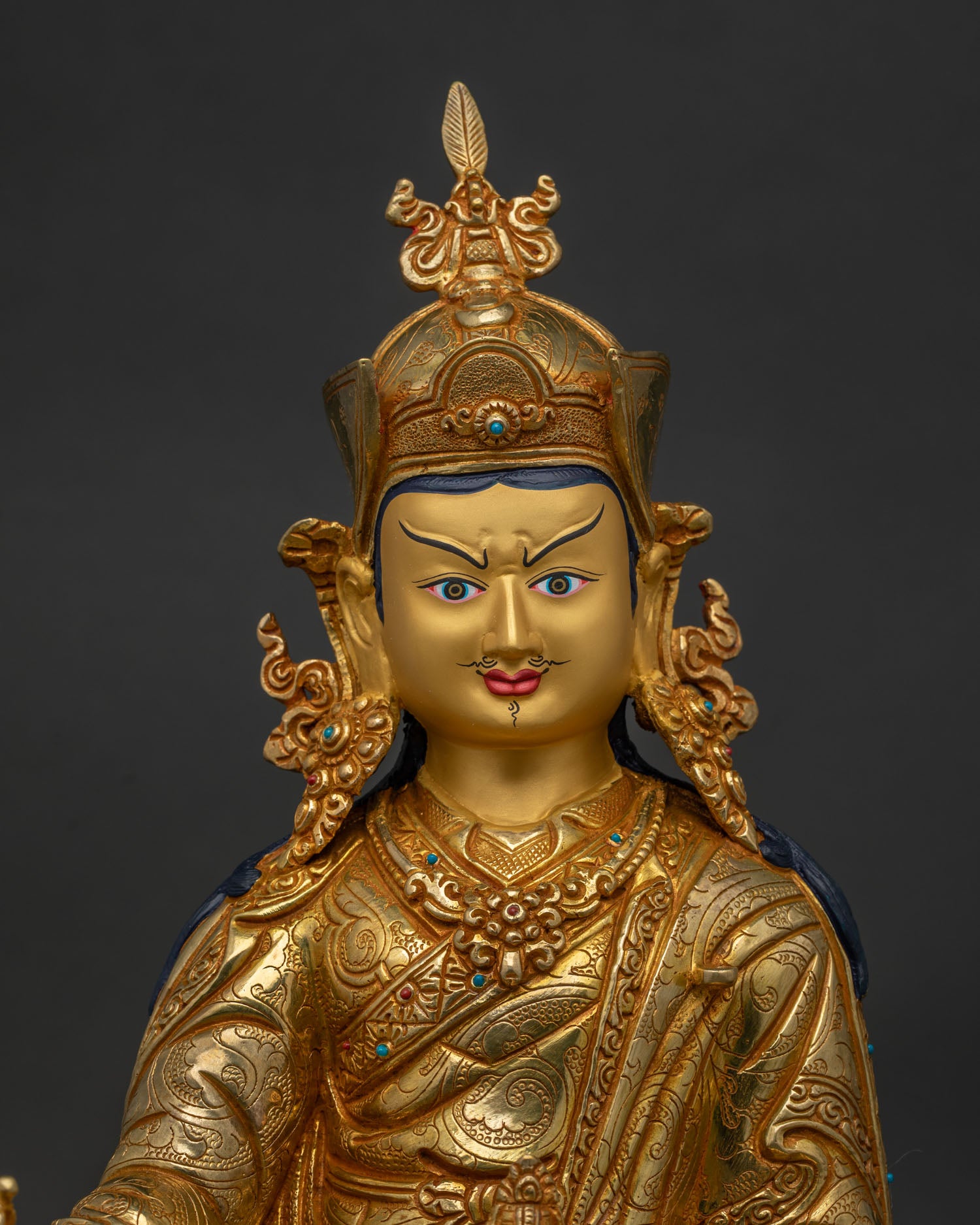 Close up of Guru Rinpoche with gold painted face and semi precious stones.