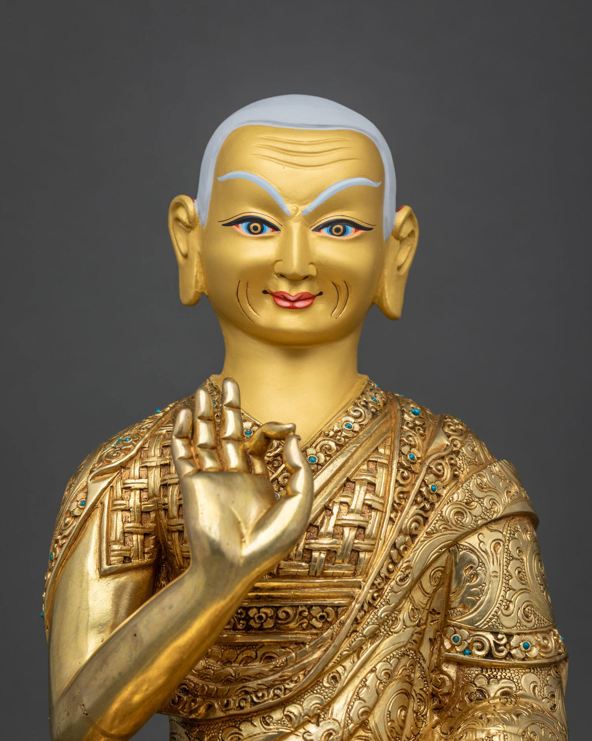 Close-up of Gyaltsab Je face with white hair, raised right hand and turquoise inlay on robe