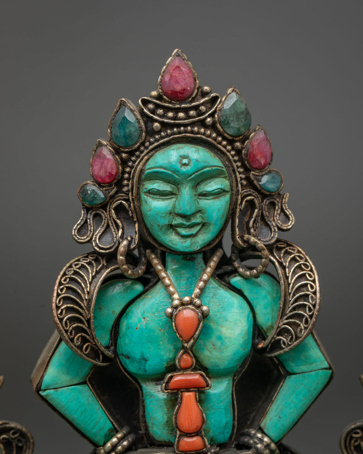 Close-up of hand-carved turquoise Amitayus face with gemstone crown and coral vase pendant
