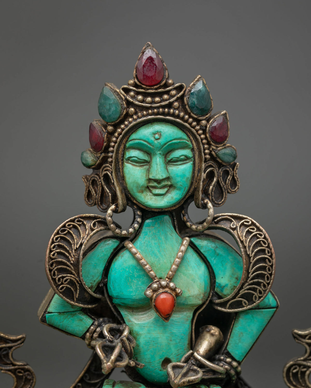 Close-up of hand-carved turquoise Vajrasattva face with gemstone crown and filigree details