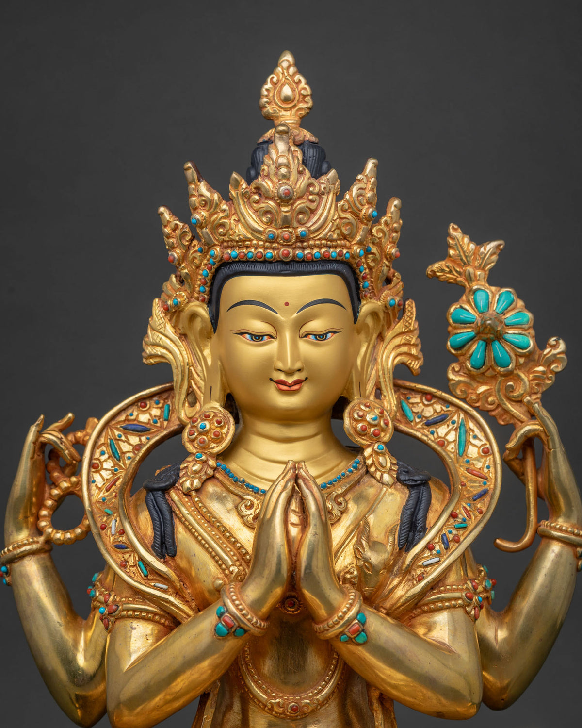 Close-up of hand-cast Chenrezig statue showing gold gilding and stone inlay
