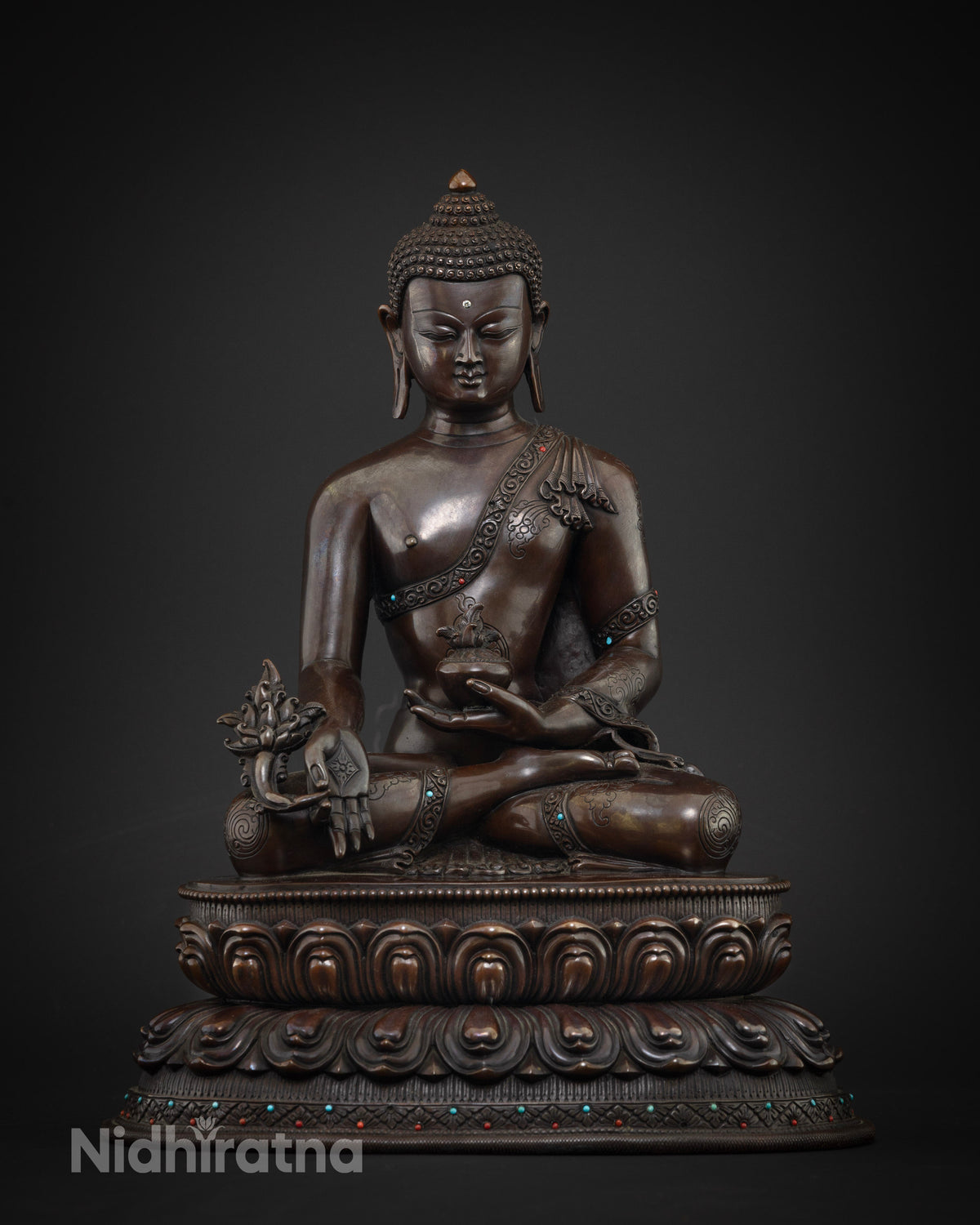 Close up of handcrafted copper Medicine Buddha statue with lotus base and semi-precious stones