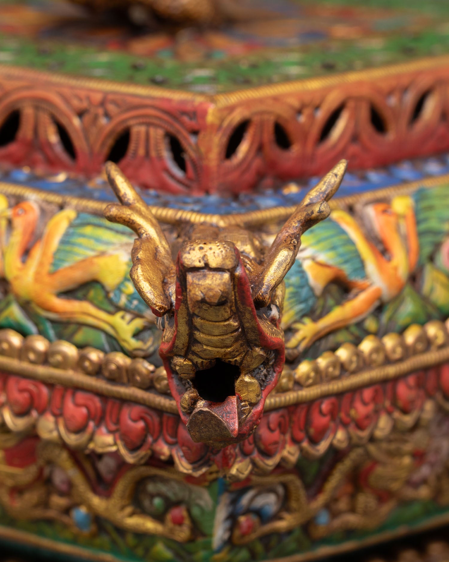 close-up of handcrafted incense holder lid with dragon heads and intricate buddhist carvings in gold finish